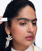Woman applying mascara with a brush on a white background