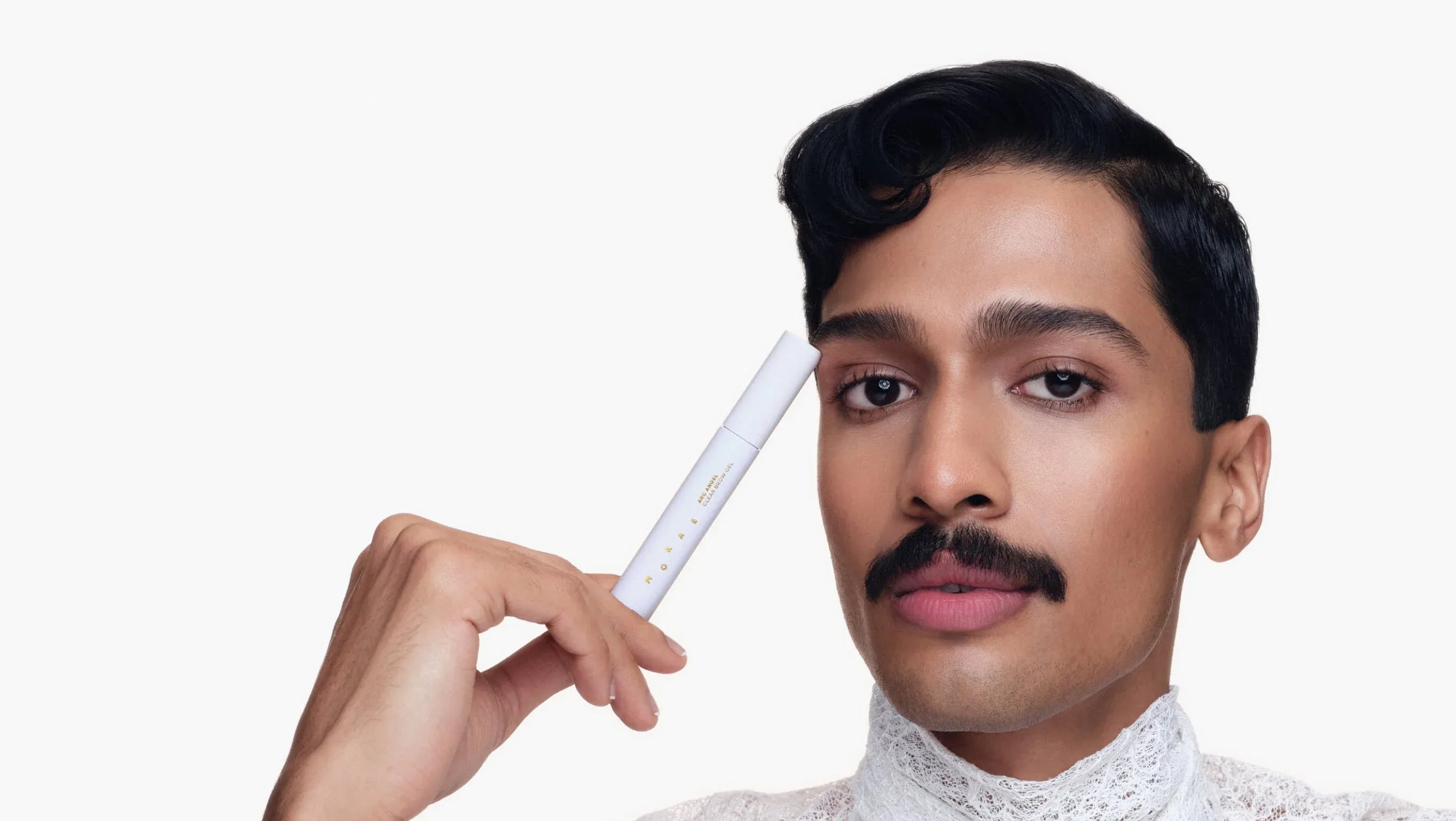 Person holding a Mokae Brow Gel to their forehead against a white background