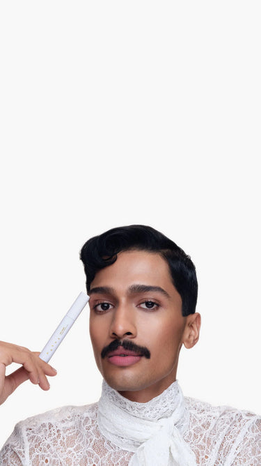 Person holding a Mokae Brow Gel to their forehead against a white background