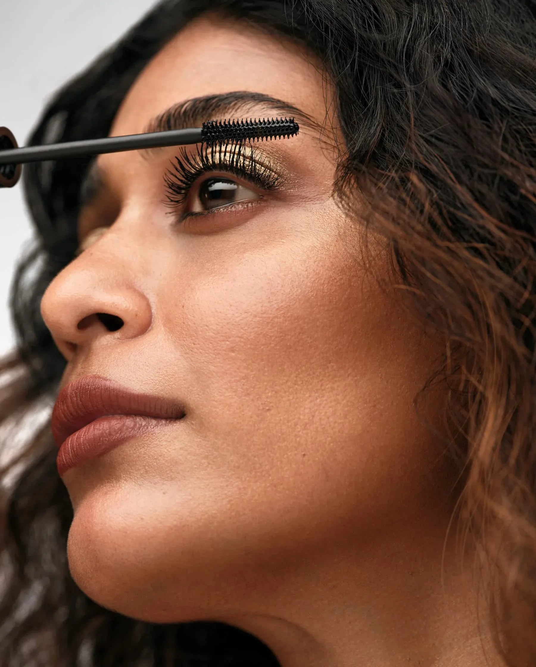 Woman applying mascara to her eyelashes with a brush