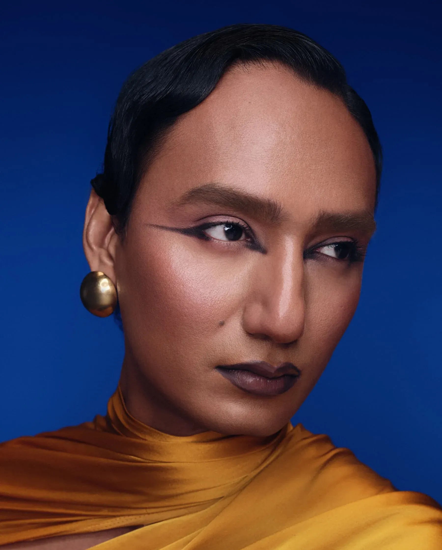 Person wearing a mustard yellow top against a blue background